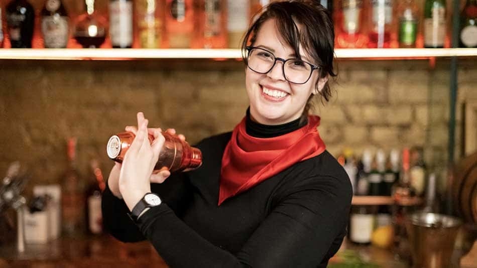 Mixologist preparing a cocktail in a cocktail shaker.