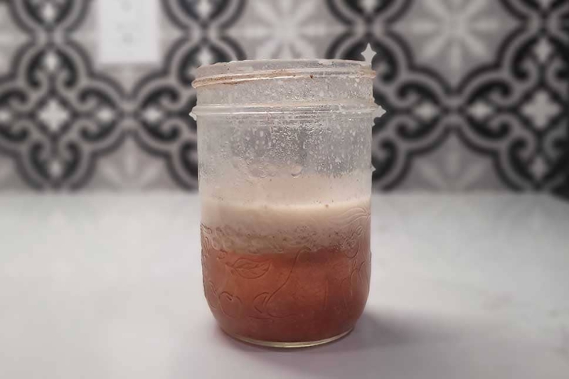 Frozen jar of bacon fat-washed bourbon with fat layer on top.