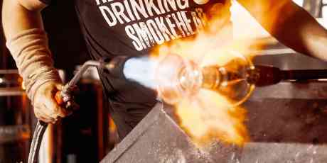Elliot Walker holding a torch blowing glass.