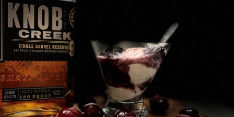 Smoked Bourbon Cherry Sauce over ice cream with a bottle of bourbon.