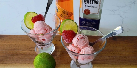 Two bowls of Strawberry Margarita Ice Cream with strawberries and lime.