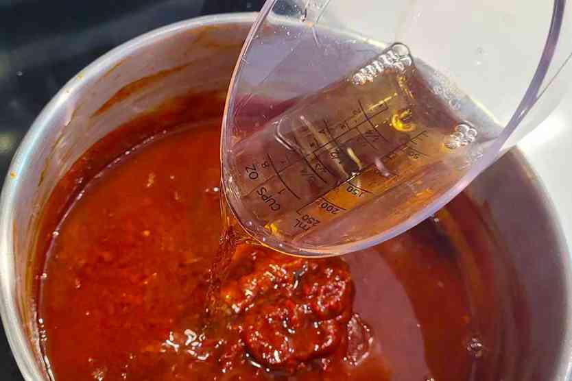 Pouring Bourbon into BBQ Sauce.
