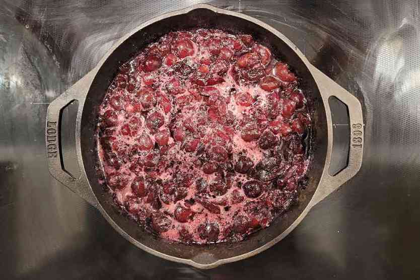 Smoked cherries in a cast iron pan on the stove.