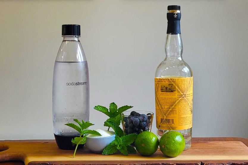 Blueberry mojitos ingredients including rum, lime, mint, and blueberries..